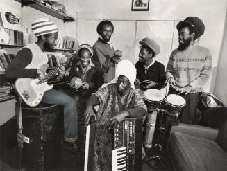 A reggae band of 6 smiling Jamaican men, holding their instruments with joy