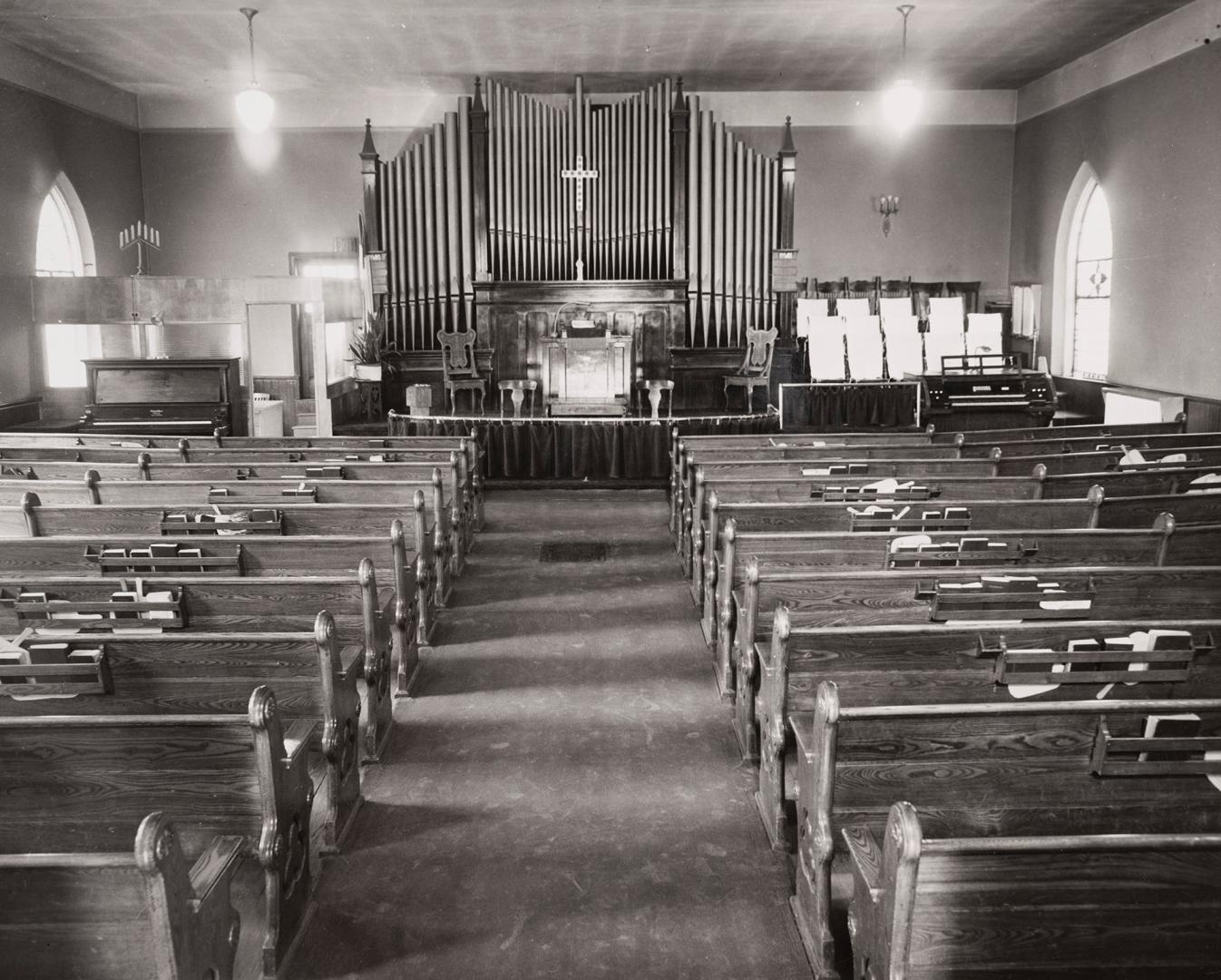 interior of church with wooden pews, an organ and a piano