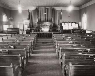 interior of church with wooden pews, an organ and a piano