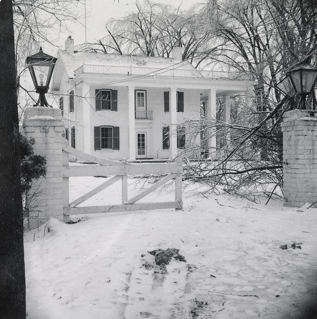 black and white photograph taken from the front gate of a two story house. 