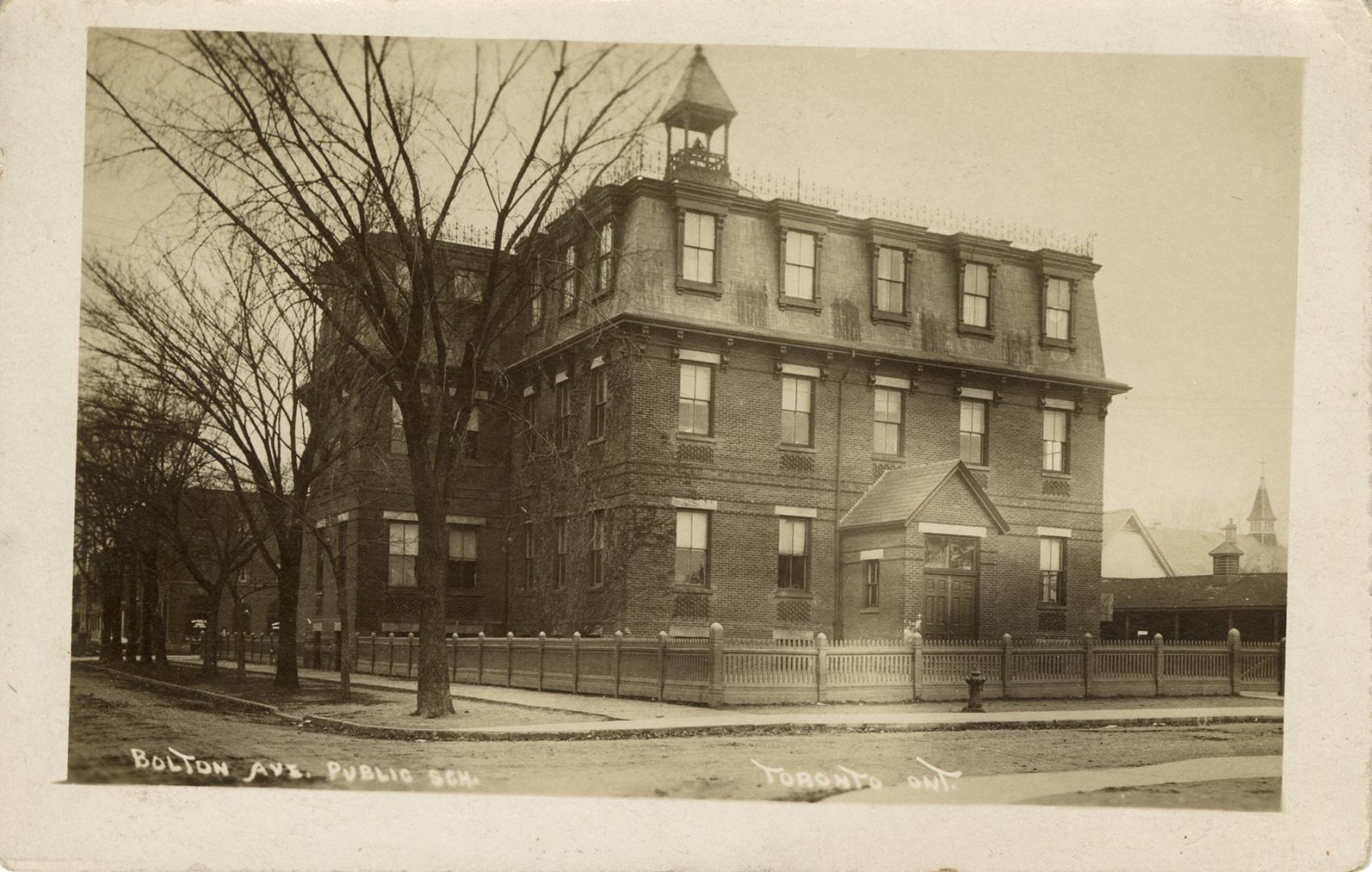 Black and white photograph of a, three story, school building with a bell tower.