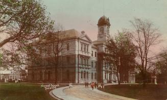 Colorized photograph of a large, three story, white stone, Victorian building with a cupola tow ...
