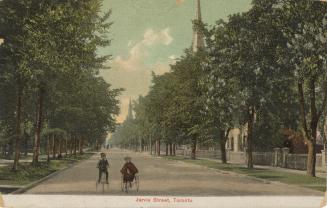 Colorized photograph of a city street bordered by large houses and trees. Two children are ridi ...