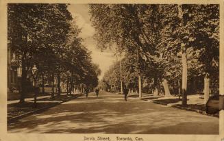 Sepia toned photograph of a city street bordered by large houses and trees.