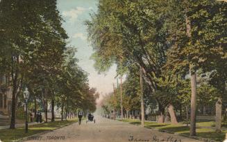 Colorized photograph of a city street bordered by large trees. People and carriages on the stre ...
