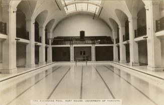 Black and white photograph of a large indoor swimming pool with a domed skylight.