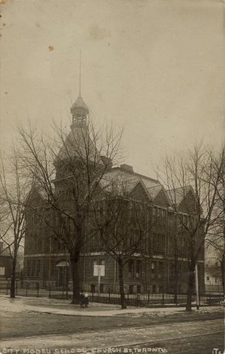Black and white photograph of a four story Victorian school with a central bell tower.