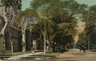 Colorized photograph of a people walking on a tree lined city street.