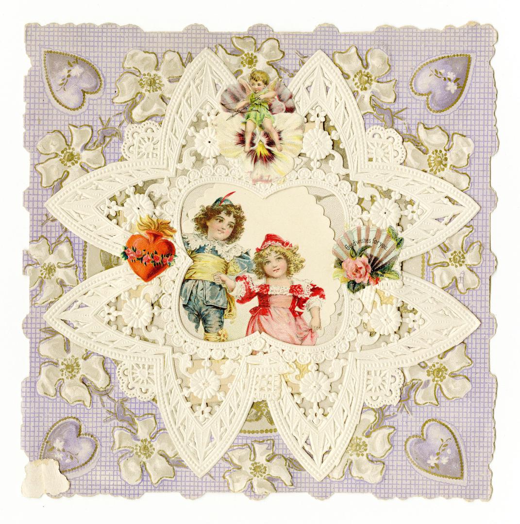 At the centre of the card a boy and girl hold hands. They are surrounded by lace décor, a cheru ...